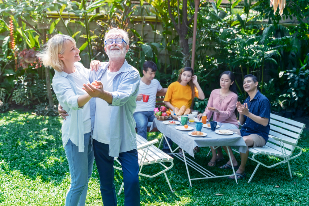 The photo above shows a multigenerational group enjoying fellowship. They are engaged in conversation while an older man is dancing with a younger woman.