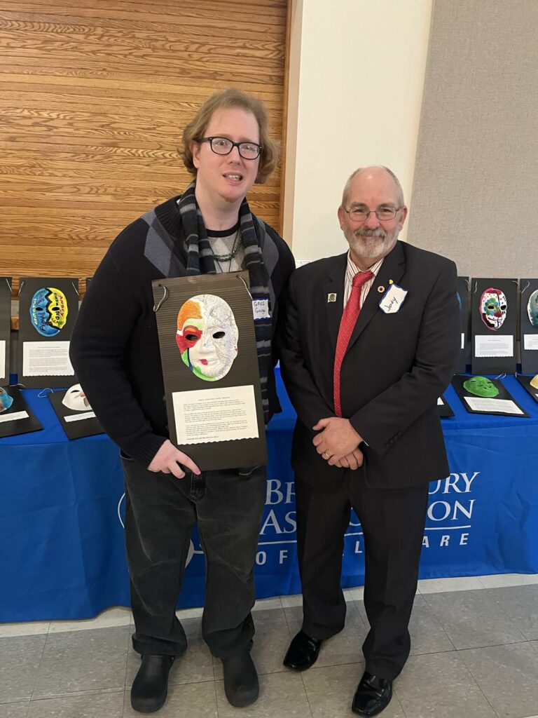 Brain injury survivor, Greg, with Kent County Levy Court Commissioner Sweeney. Greg is holding the mask he painted as a part of a special art therapy workshop BIADE hosted in 2020.